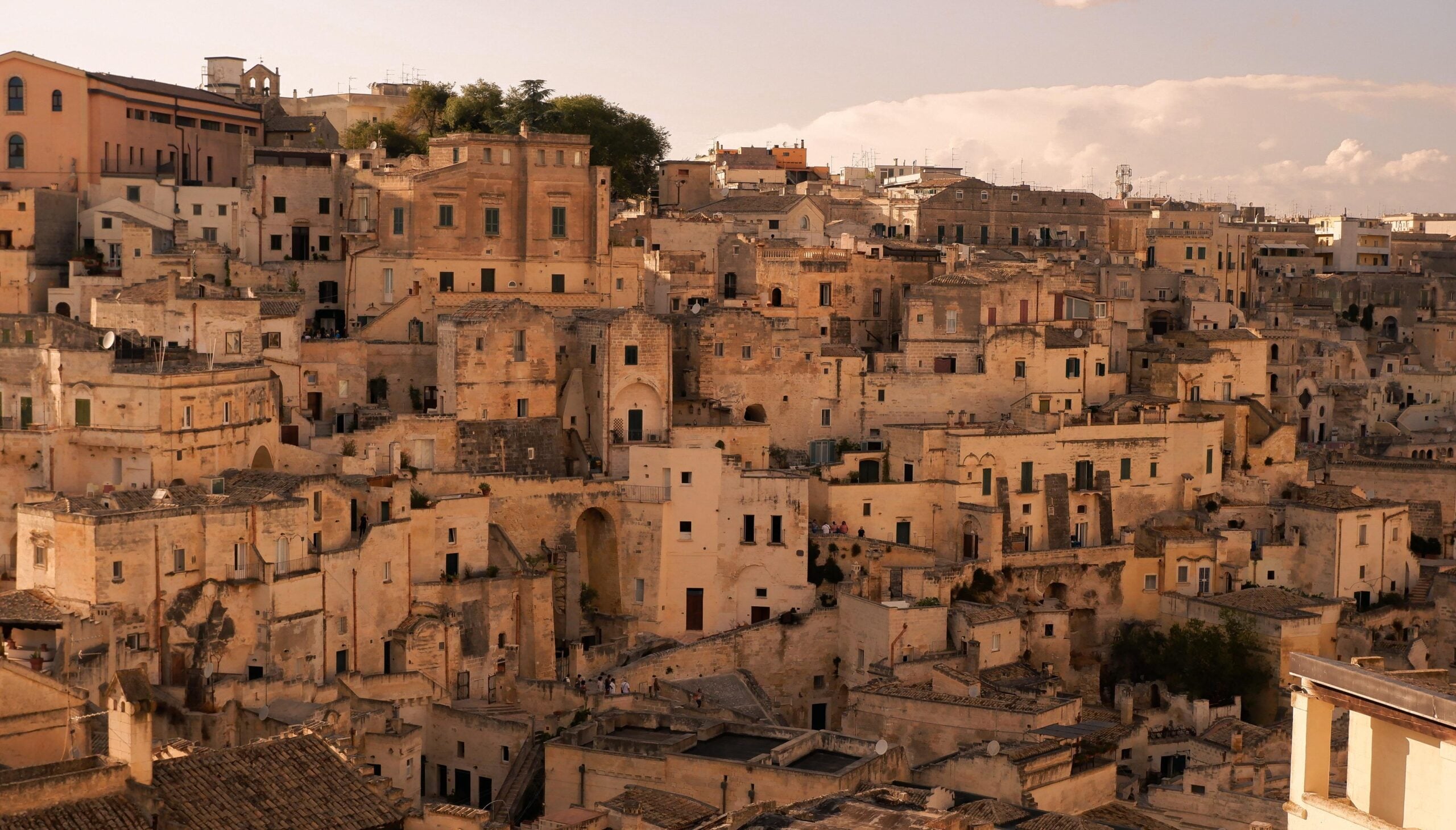 Une ville à flanc de colline, densément peuplée, avec des bâtiments en pierre beige de tailles et de hauteurs différentes, des toits plats et en tuiles, de petites fenêtres et des rues étroites - une toile de fond idéale pour explorer les pouilles à vélo sous un ciel partiellement nuageux. - Ekilib