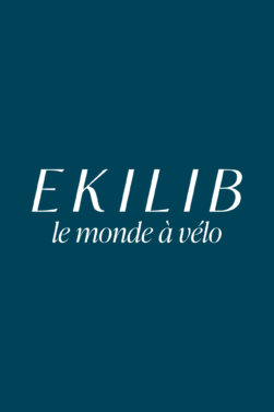 Le texte blanc sur fond sarcelle indique EKILIB en grandes lettres, avec la phrase le monde à vélo en plus petites lettres cursives, représentant la passion de l'Équipe Ekilib pour les aventures cyclistes. - Ekilib